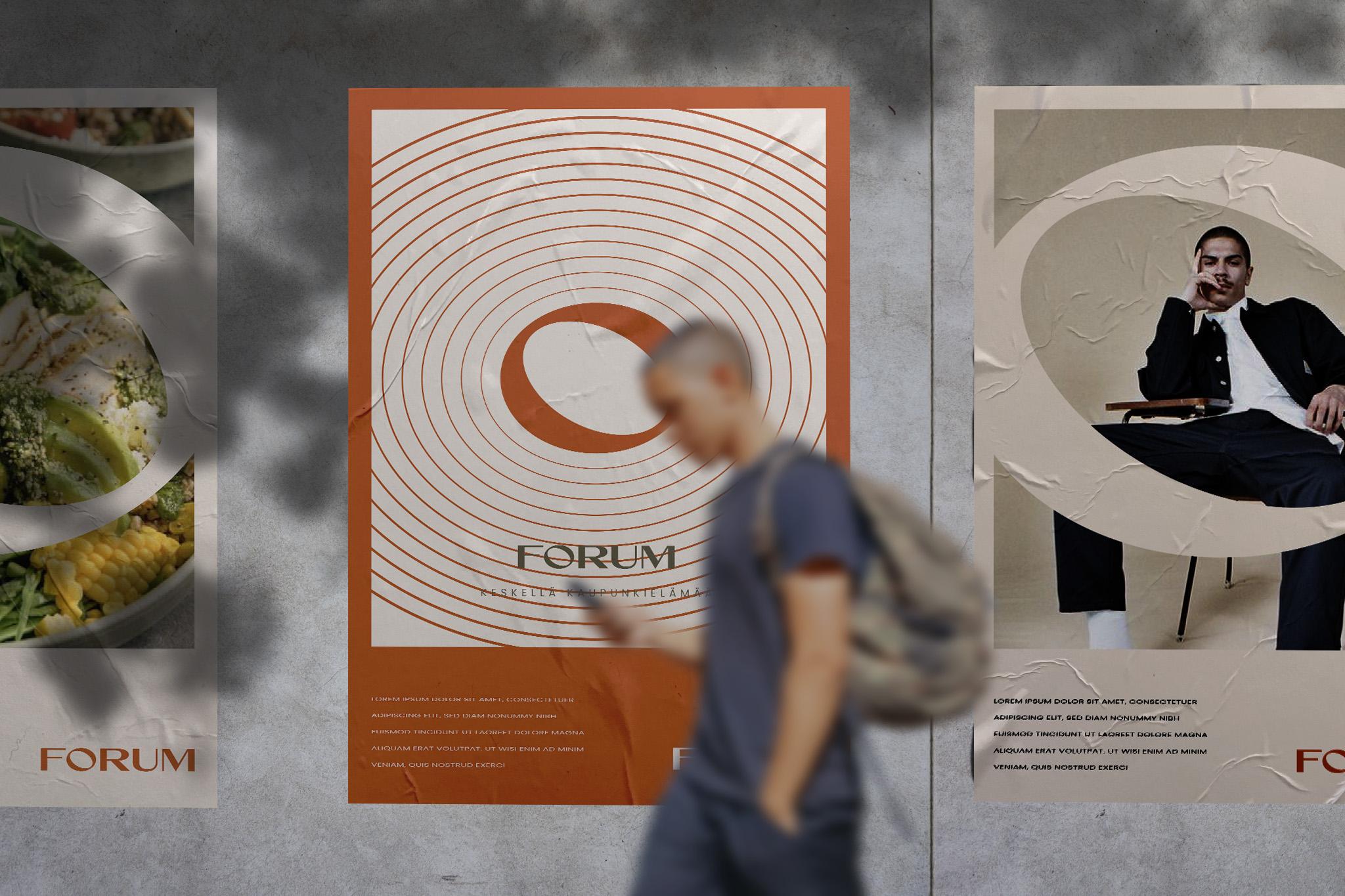 Kolme mainosjulistetta kauppakeskus Forumille, joista keskimmäisessä oranssi spiraalimuotoilu ja Forumin logo. Kuvan etualalla kulkee blurrattu henkilö.